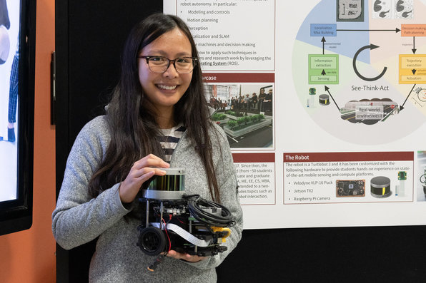Presenter standing in front of poster holding project